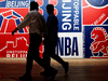 Men walk past a poster at an NBA exhibition in Beijing, China on Oct. 8, 2019.