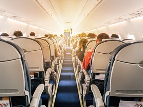 ommercial aircraft cabin with rows of seats down the aisle.