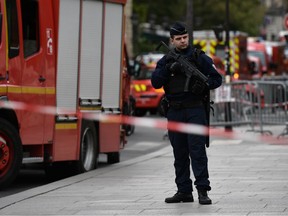 A policeman stands next to firefighter vehicles near Paris prefecture de police (police headquarters) on October 3, 2019 after four officers were killed in a knife attack.
