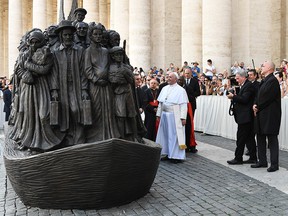 Pope Francis attends the unveiling of a sculpture called "Angels Unawares" by Canadian sculptor Timothy Schmalz, seen at far right, depicting a group of 140 migrants of various cultures and from different historic times, following a mass for World Day of Migrants and Refugees on Sept. 29, 2019, at St. Peter's Square in the Vatican.
