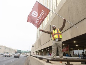 SaskTel employee Ryan Cleniuk waves to drivers in the hope of a supportive "honk" near a SaskTel building on Saskatchewan Drive in downtown Regina on Friday, October 4, 2019.