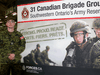 Reservist Cpl. Evan White stands next to a recruitment poster in April 2019.