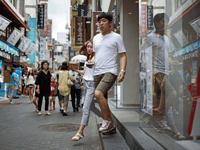 A couple exit a shop in the popular Myeongdong shopping area in Seoul, South Korea. "That attitude of saying, ‘Come what may. Let’s have a good time, not a long time’ — these are sentiments that have been around for quite a long time," a Canadian linguist says.