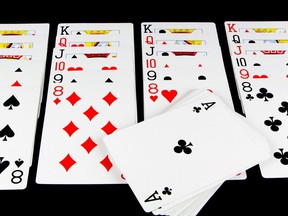 Playing cards being used for solitaire on black background .