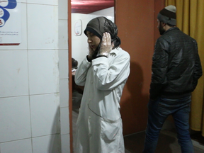 Dr. Amani Ballour covers her ears during a bombardment, in a scene from The Cave.