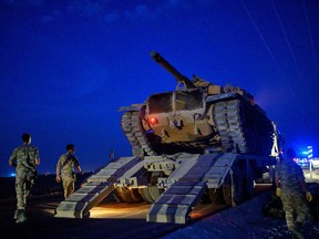 A tank trundles down from a truck as Turkish armed forces approach the border with Syria near Akcakale in Sanliurfa province on October 8, 2019.