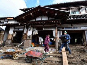 Residents clean their flood-damaged home in Nagano on October 15, 2019, after Typhoon Hagibis hit Japan on October 12 unleashing high winds, torrential rain and triggered landslides and catastrophic flooding. - The death toll from the disaster has risen steadily, and the national broadcaster early on October 15 said 58 people had been killed, according to authorities, while more than a dozen were still missing.