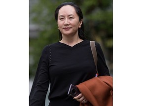 Huawei chief financial officer Meng Wanzhou, who is out on bail and remains under partial house arrest after she was detained last year at the behest of American authorities, carries one of her company's phones as she leaves her home to attend a court hearing in Vancouver, on Wednesday October 2, 2019.