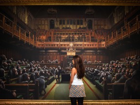 A gallery worker poses with the Banksy painting "Devolved Parliament" at Sotheby's on Sept. 27, 2019, in London, England.