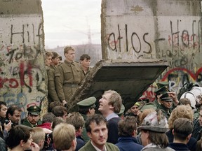 West Berliners crowd in front of the Berlin Wall early 11 November 1989 as they watch East German border guards demolishing a section of the wall in order to open a new crossing point between East and West Berlin, near the Potsdamer Square.
