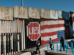 People walk along the border fence at the beach in city of Tijuana on January 19, 2019 in Tijuana, Mexico.