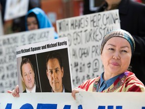 Turnisa Matsedik-Qira, of the Vancouver Uyghur Association, demonstrates against China's treatment of Uyghurs while holding a photo of detained Canadians Michael Spavor (L) and Michael Kovrig outside a court appearance for Huawei Chief Financial Officer, Meng Wanzhou at the British Columbia Supreme Court in Vancouver on May 8, 2019.