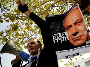 Protesters hold signs as they take part in a rally calling upon Israeli Prime Minister Benjamin Netanyahu to step down in Tel Aviv, Israel February 16, 2018.