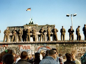 In this file photo taken on November 11, 1989 East German border guards stand on a section of the Berlin wall with the Brandenburg gate in the background in Berlin.