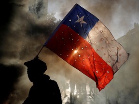 A demonstrator waves a Chile flag riddled with holes during a protest against Chile's government in Santiago, Chile October 31, 2019.