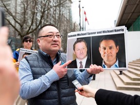 Louis Huang of Vancouver Freedom and Democracy for China holds photos of Canadians Michael Spavor and Michael Kovrig, who are being detained by China, outside British Columbia Supreme Court, in Vancouver, on March 6, 2019, as Huawei Chief Financial Officer Meng Wanzhou appears in court.