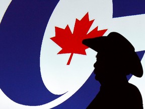 A man is silhouetted in front of a Conservative logo at a party leadership forum in Calgary on March 1, 2017.