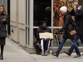 A man, center, panhandles on the street Monday, Jan. 25, 2016, in Chicago. A bylaw targeting certain panhandlers has been approved in the Metro Vancouver city of Maple Ridge.