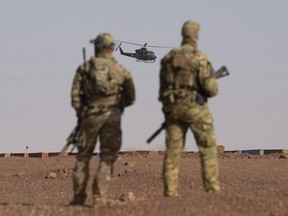 Canadian soldiers watch as a Canadian Gryphon helicopter provides air security during a demonstration for Prime Minister Justin Trudeau on the United Nations base in Gao, Mali, Saturday, Dec. 22, 2018.