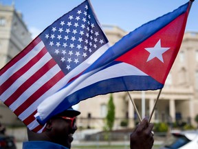 A man holds holds American and Cuban flags across the street from the Cuban embassy in Washington, D.C., U.S., on Monday, July 20, 2015.