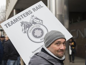 A CN rail worker holds up a sign outside CN headquarters in Montreal, Tuesday, Nov. 26, 2019.