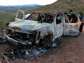 Members of the Lebaron family inspect the burned car where some of the nine murdered members of their family were killed during an armed ambush on Bavispe, Sonora mountains, Mexico, Nov. 5, 2019.