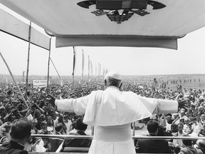 John Paul II rides in the Popemobile with his arms outstretched to the crowd during an eight-day visit to Poland in June 1979.