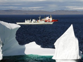 Two Canadian ships sail past an iceberg in the Hudson Strait off the coast of Baffin Island.