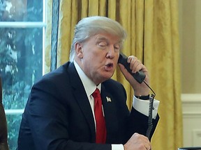 President Donald Trump is seen through a window speaking on the phone with King of Saudi Arabia, Salman bin Abd al-Aziz Al Saud, in the Oval Office of the White House, January 29, 2017 in Washington, D.C.