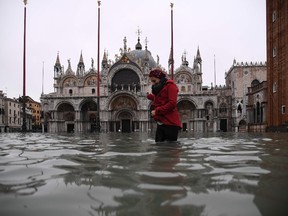 A woman  crosses the flooded St. Mark's squareby St. Mark's Basilica after an exceptional overnight "Alta Acqua" high tide water level, early on November 13, 2019 in Venice.