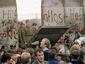 In this file photo taken on November 11, 1989 West Berliners crowd in front of the Berlin Wall early as they watch East German border guards demolishing a section of the wall in order to open a new crossing point between East and West Berlin, near the Potsdamer Square in Berlin.