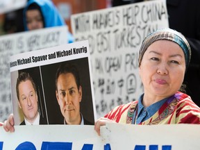 Turnisa Matsedik-Qira, of the Vancouver Uyghur Association, demonstrates against China's treatment of Uyghurs while holding a photo of detained Canadians Michael Spavor (L) and Michael Kovrig outside a court appearance for Huawei Chief Financial Officer, Meng Wanzhou at the British Columbia Supreme Court in Vancouver on May 8, 2019.