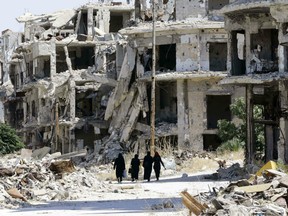 Syrian women walk in between destroyed buildings in the government-held Jouret al-Shiah neighbourhood of the central Syrian city of Homs on September 19, 2016.