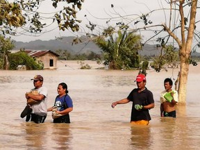 Residents wade through a flooded highway, caused by heavy rains due to typhoon Phanfone, in Ormoc City, Leyte province in central Philippines on December 25, 2019.