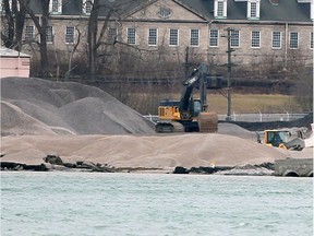 Heavy machinery move tons of crushed stone around the Detroit, Michigan shoreline at Detroit Bulk Storage Wednesday. Historic Fort Wayne is shown behind.