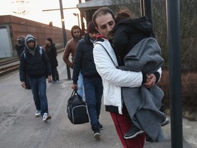 Migrants, many of them from Syria, walk to police vans after police found them while checking the identity papers of passengers on a train arriving from Germany on January 6, 2016 in Padborg, Denmark.