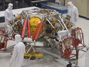 NASA engineers and technicians examine the descent stage of the Mars 2020 spacecraft, Dec. 27, 2019 during a media tour of the Mars2020 Spacecraft Assembly Facility clean room at NASA's Jet Propulsion Laboratory in Pasadena, Calif.