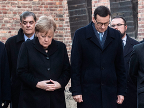 German Chancellor Angela Merkel (L) and Polish Prime Minister Mateusz Morawiecki pay their respects after laying wreaths during her visit to the former German Nazi death camp Auschwitz-Birkenau in Oswiecim, Poland on Dec. 6, 2019.