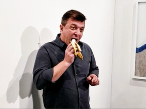 David Datuna eats a banana that was attached with duct tape to a wall — which was an artwork titled Comedian.