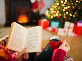 A woman reads a book while drinking coffee during Christmas.