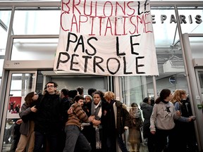 A banner reading "Burn the capitalism not oil" is displayed at a demonstration in La Defense business district on the outskirts of Paris on Nov. 29, 2019.