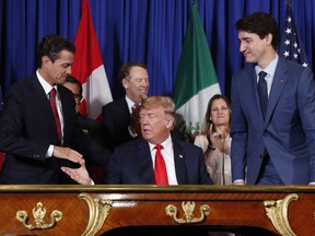 President Donald Trump shakes hands with Mexico President Enrique Pena Neto, left, as Canada's Prime Minister Justin Trudeau, right, looks on after participating in the USMCA signing ceremony, Friday, Nov. 30, 2018 in Buenos Aires, Argentina. A deal on amending the new North American free trade agreement appears close following a busy weekend, with hopes Canada, Mexico and the United States will approve a rewritten deal in the next 24 hours.