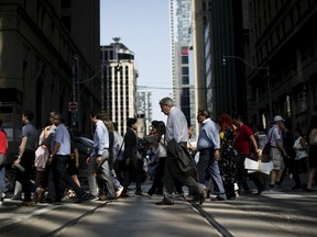 Pedestrians cross a street in the financial district of Toronto, on July 25, 2019.