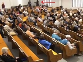 In this screenshot from the live steam, a gunman brandishes his gun in a Texas church before firing on parishioners.