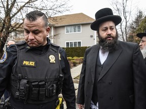 A member of the Ramapo police stands guard in front of the house of Rabbi Chaim Rottenberg on December 29, 2019 in Monsey, New York. Five people were injured in a knife attack during a Hanukkah party and a suspect, identified as Grafton Thomas, was later arrested.