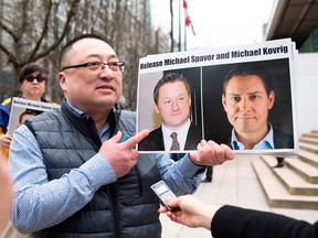 Louis Huang of Vancouver Freedom and Democracy for China holds photos of Canadians Michael Spavor and Michael Kovrig, who are being detained by China, outside British Columbia Supreme Court in Vancouver on March 6, 2019.
