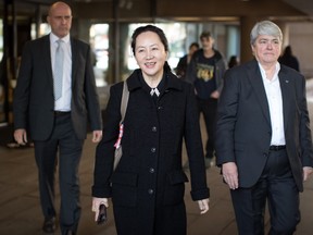 Huawei chief financial officer Meng Wanzhou, centre, who is out on bail and remains under partial house arrest after she was detained last year at the behest of American authorities, is escorted by members of a private security team as she leaves B.C. Supreme Court during a lunch break from a hearing, in Vancouver, on Sept. 24, 2019.