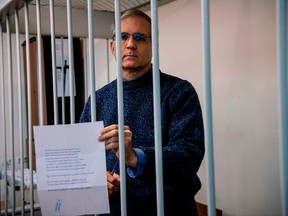 U.S.-British Paul Whelan, a former US Marine accused of espionage and arrested in Russia in December 2018, holds a message as he stands inside a defendants' cage before a hearing to decide to extend his detention at the Lefortovo Court in Moscow on October 24, 2019.
