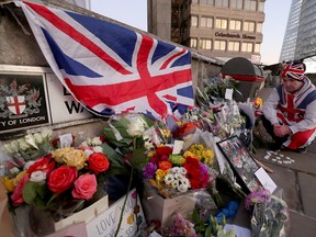 A man lights candles in front of placards and tributes to victims of the  Nov. 29, 2019, London Bridge terrorism attack, in which two were killed, on Dec. 2.