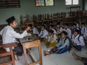 Students listening to their teacher as they study at the islamic boarding school Lirboyo during the holy month of Ramadan on June 9, 2016 in Kediri, East Java, Indonesia.